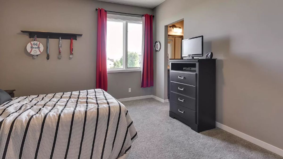 A bedroom with a bed, window, and cabinet.