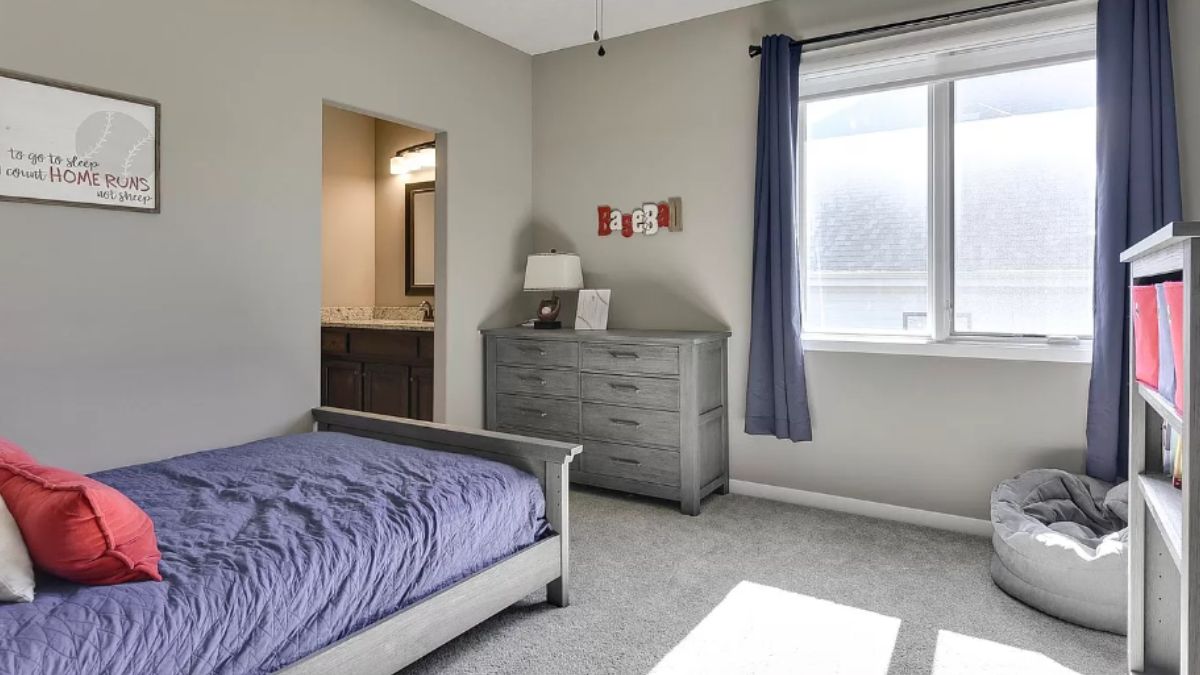 A bedroom with a bed, cabinet, and windows.