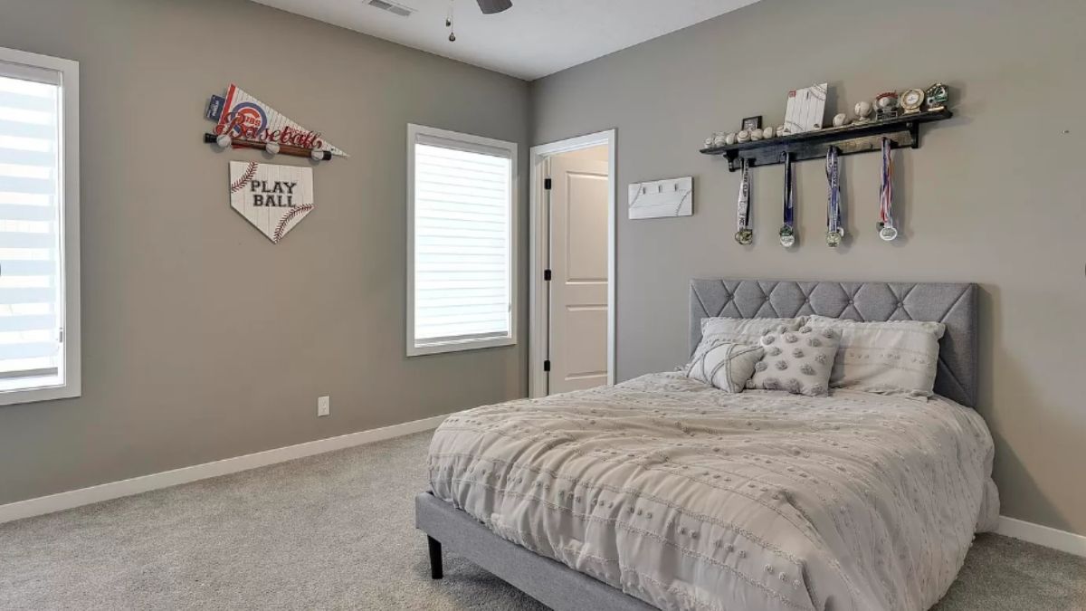 A bedroom with a bed with a headboard and windows.