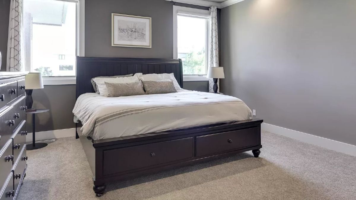 A bedroom with a bed with a headboard, cabinet, and windows.