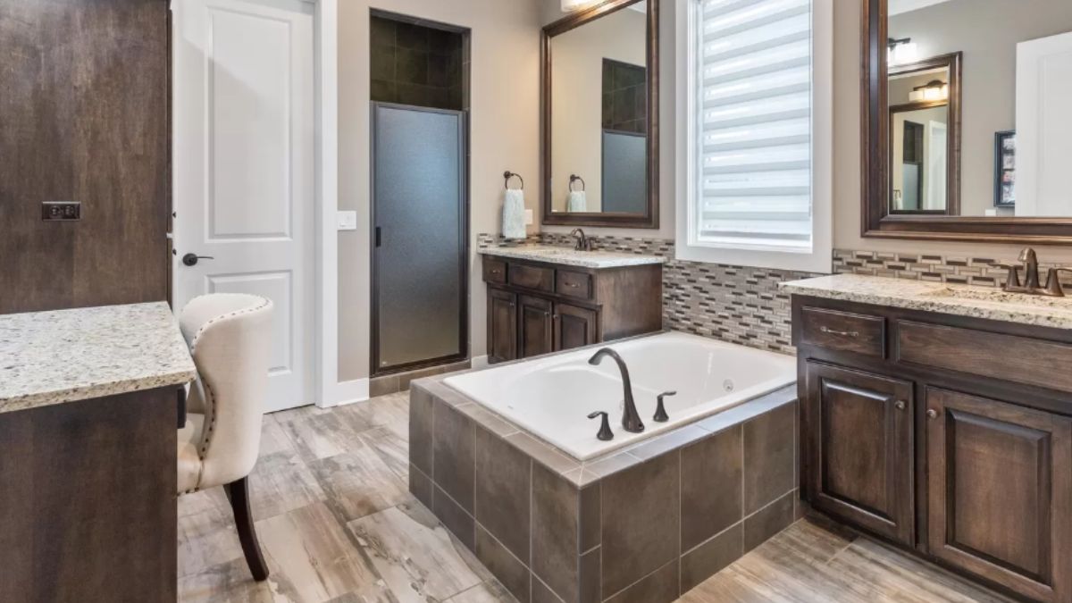 A bathroom with vanities, mirrors, bathtub, and chair.