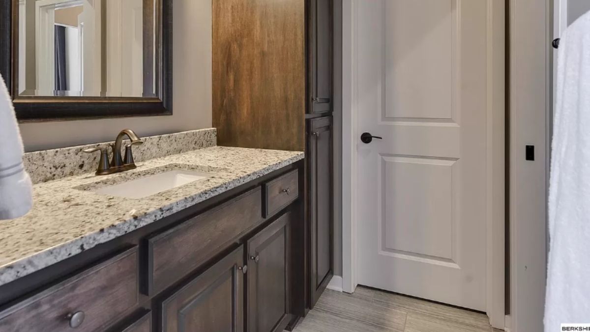 A bathroom with vanity, cabinets, and mirror.