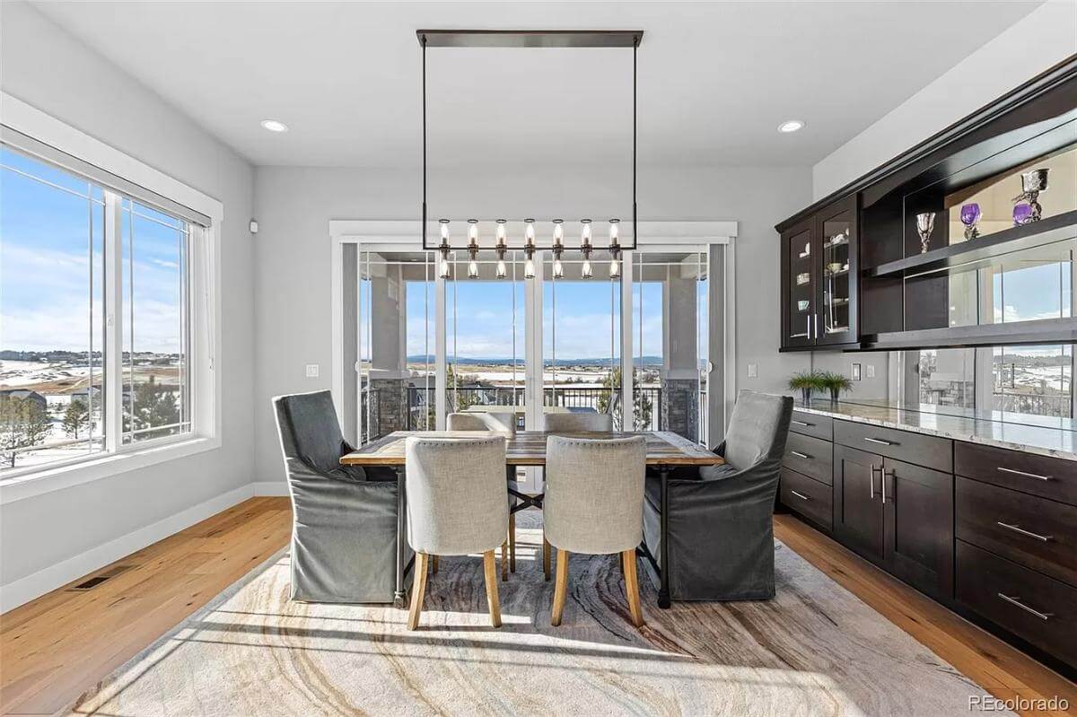 Dining area with a built-in bar and a 6-seater dining set topped by a linear chandelier.