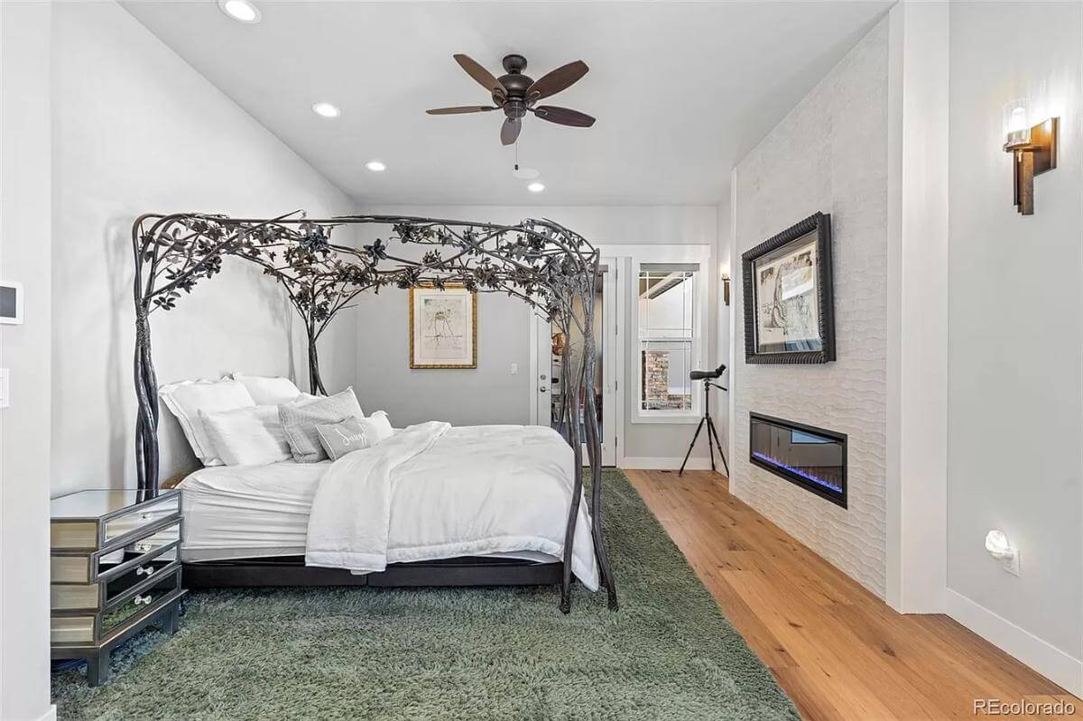 Primary bedroom with a custom canopy bed and a linear fireplace.