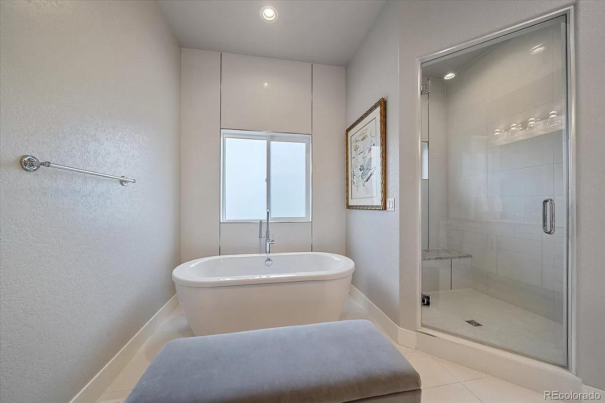 Primary bathroom showcasing the freestanding tub complemented by a large ottoman.