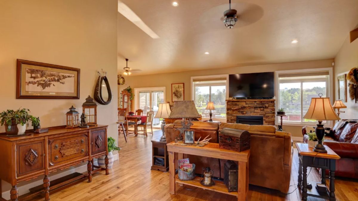 A living room with windows, a TV, fireplace, ceiling fan, cabinets, and couches.