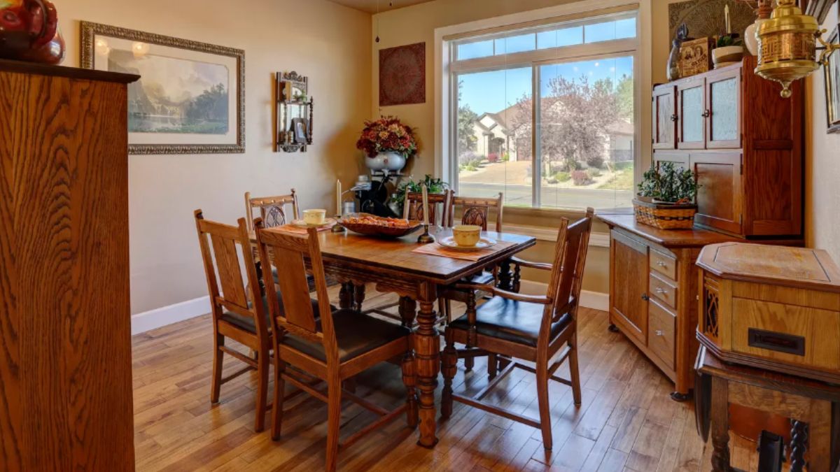 A dining room with cabinets, paintings, and a dining table surrounded by chairs.