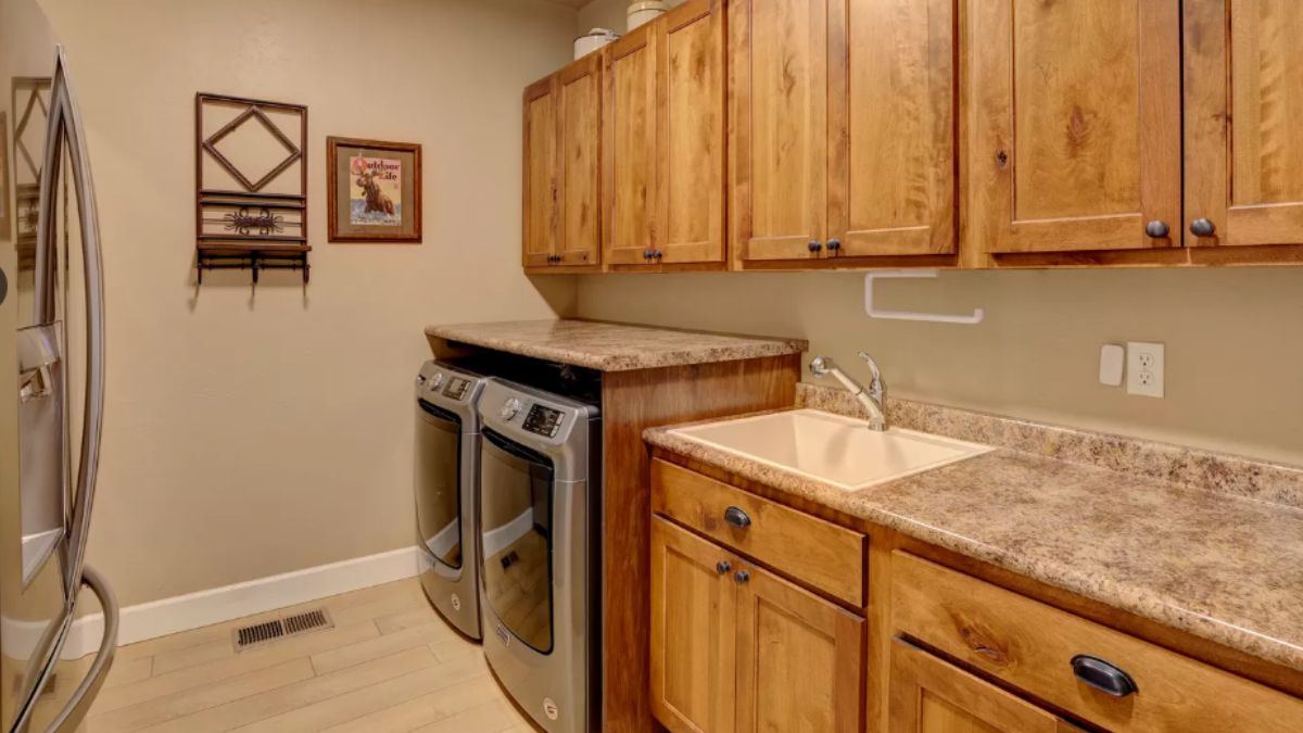 A laundry room with a sink, cabinets, and a washing machine.