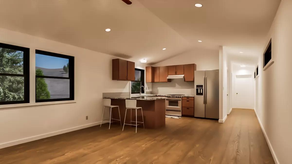 Living room and kitchen with hardwood flooring and a vaulted ceiling.