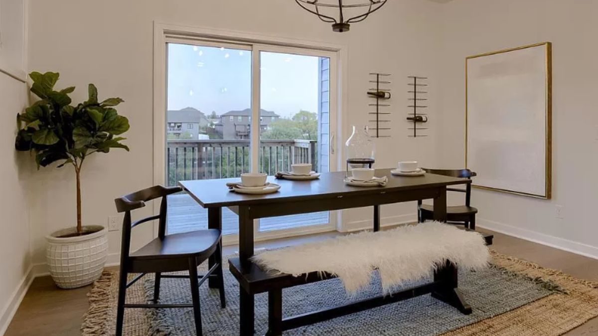 A dining room with a potted plant, a dining table with chairs, and a bench.