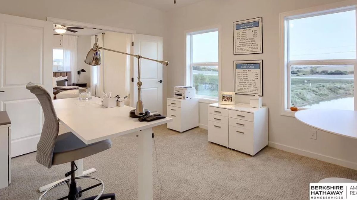 A home office with cabinets, windows, a desk, and a chair.