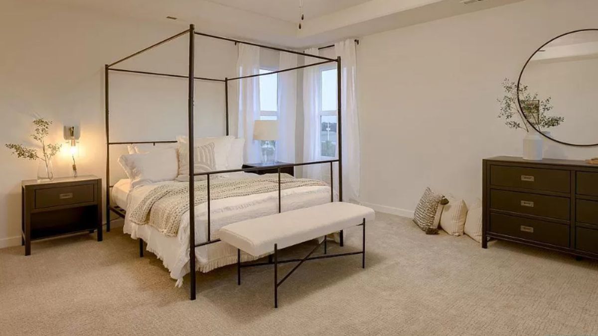 A bedroom with a canopy bed, a nightstand, cabinets, and windows.