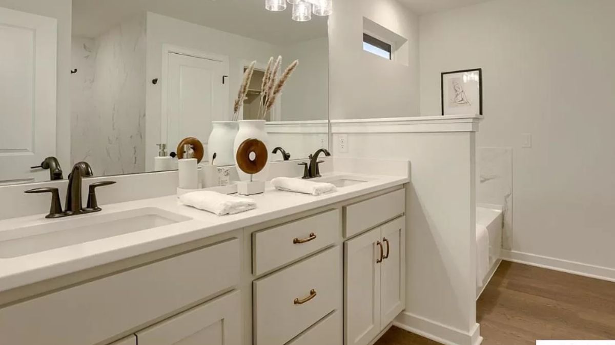 A bathroom with a vanity, cabinets, and a mirror.