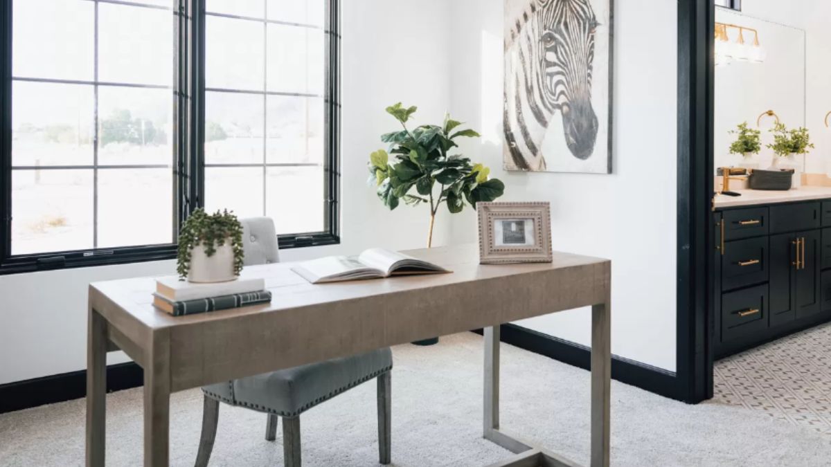 A home office with a window, painting, desk, and chair.