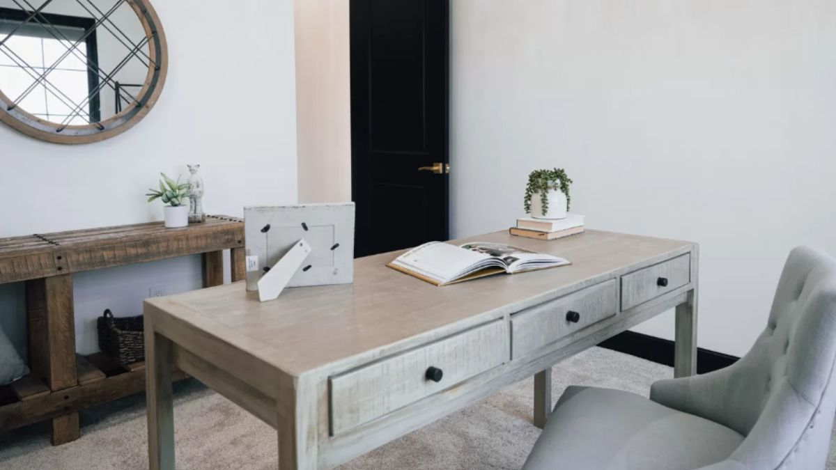 A home office with a mirror, desk, and chair.