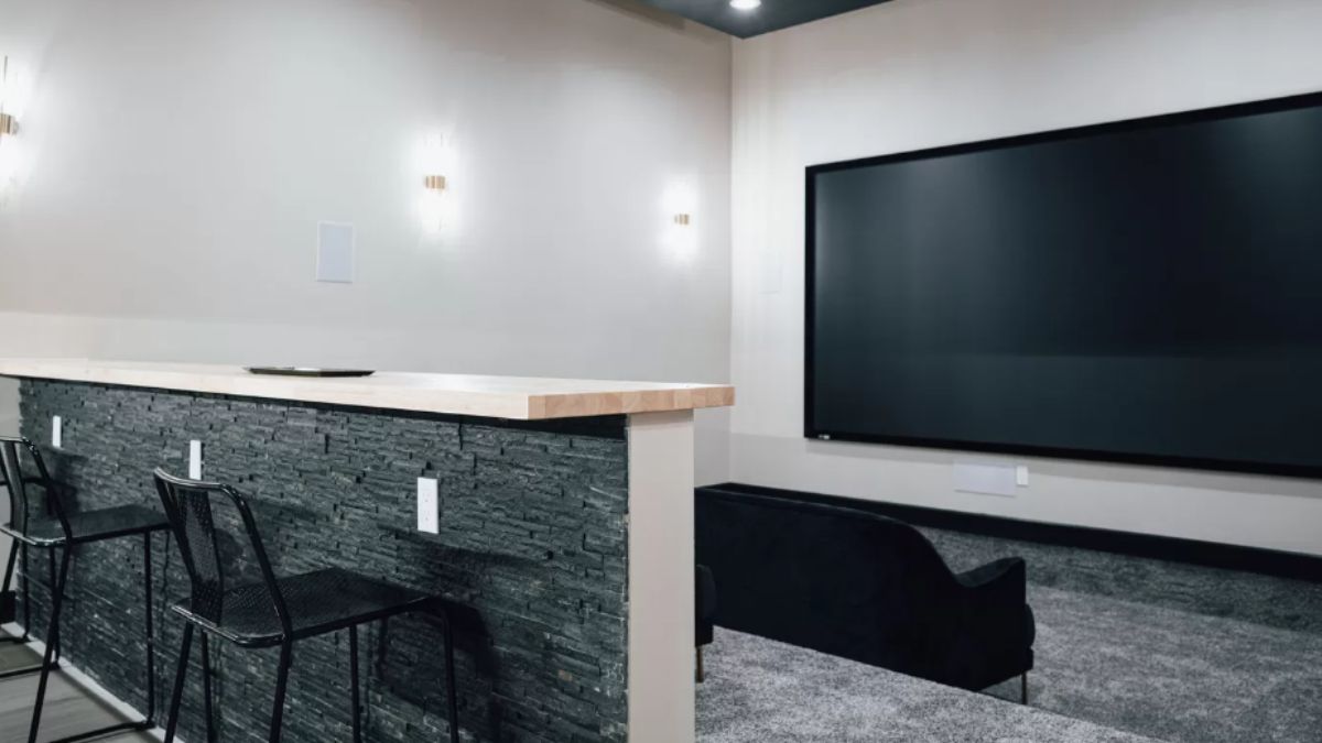 A home theater with a large screen, countertop, and chairs.