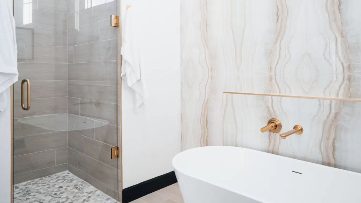 A bathroom with marble walls, a bathtub, and a shower room.