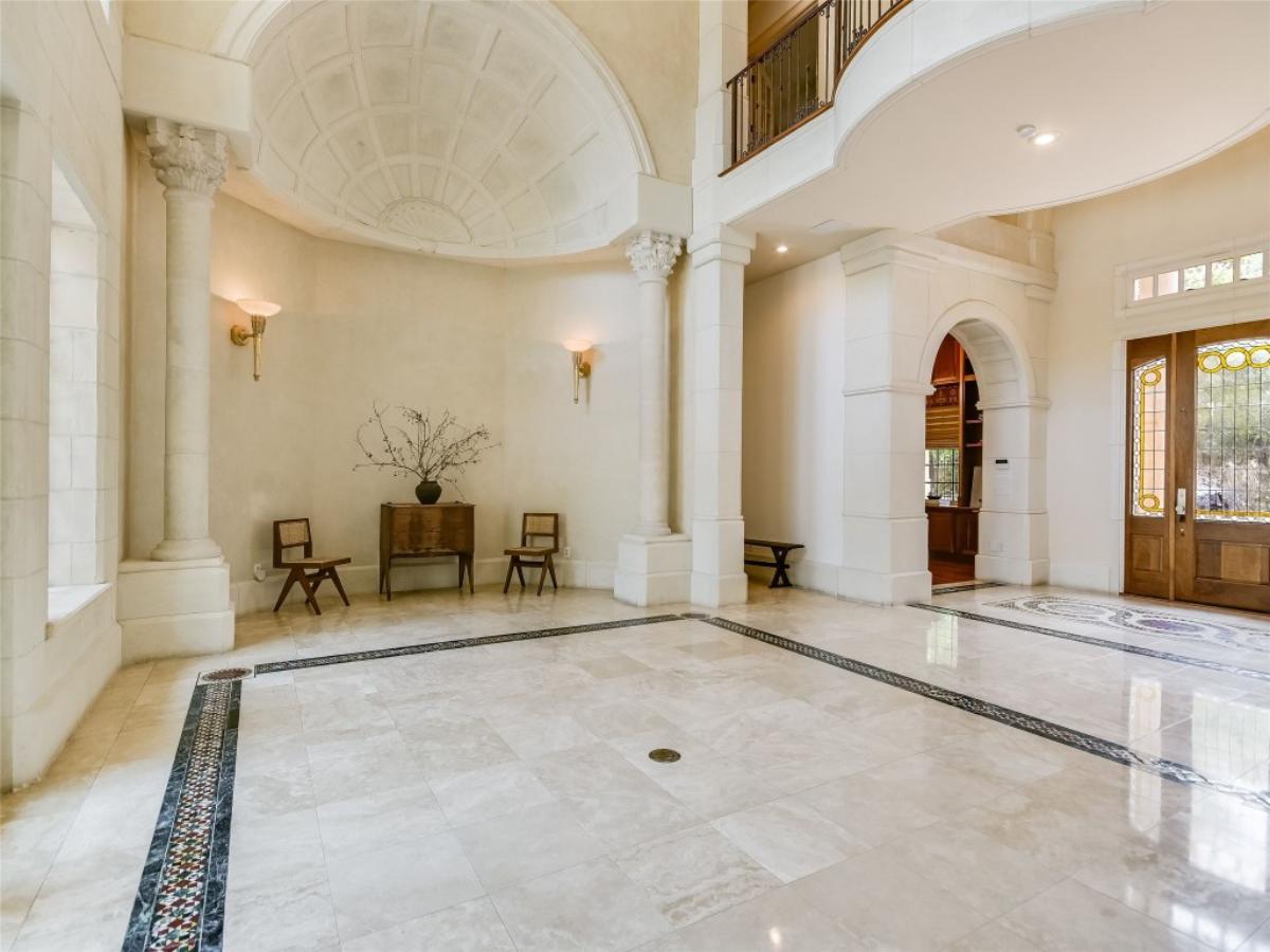 Foyer with hardwood door and soaring ceilings.