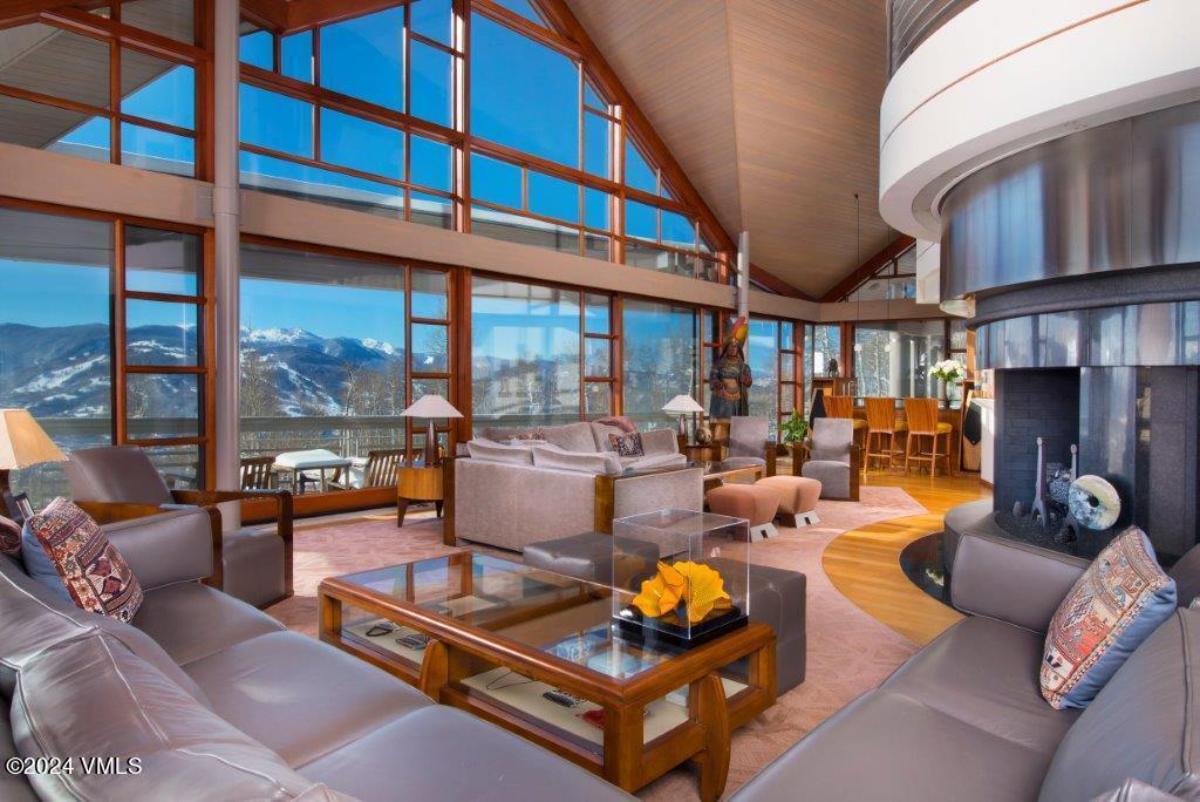 Living room with couches, a fireplace and floor-to-ceiling glass windows.