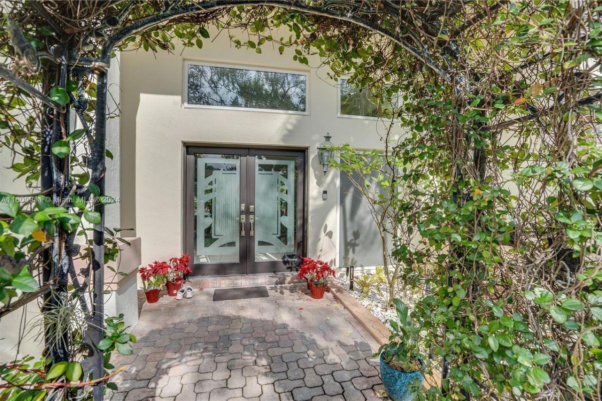 A front entry with plants and a glass door.