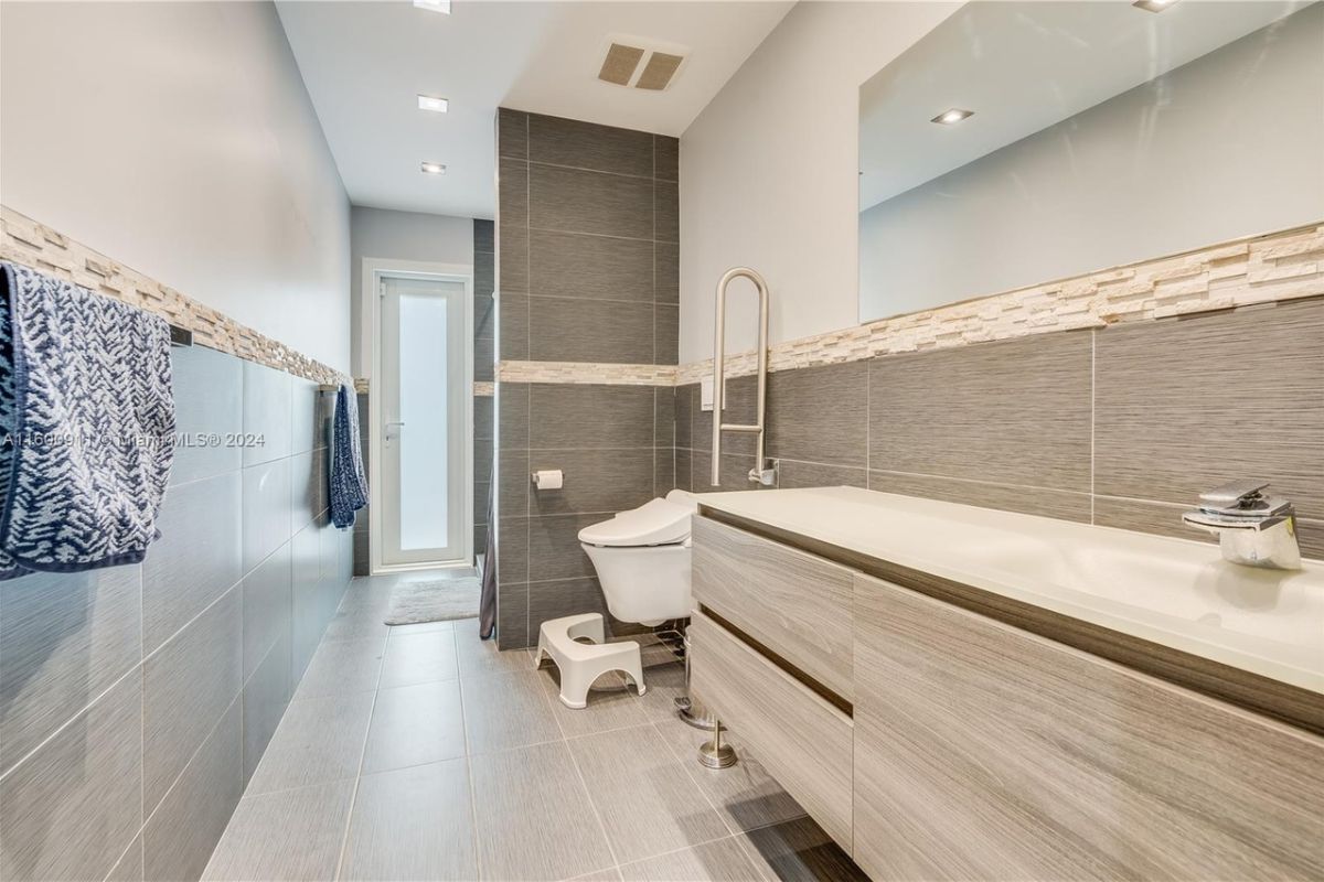 A bathroom with countertop, sink, mirror, and toilet.