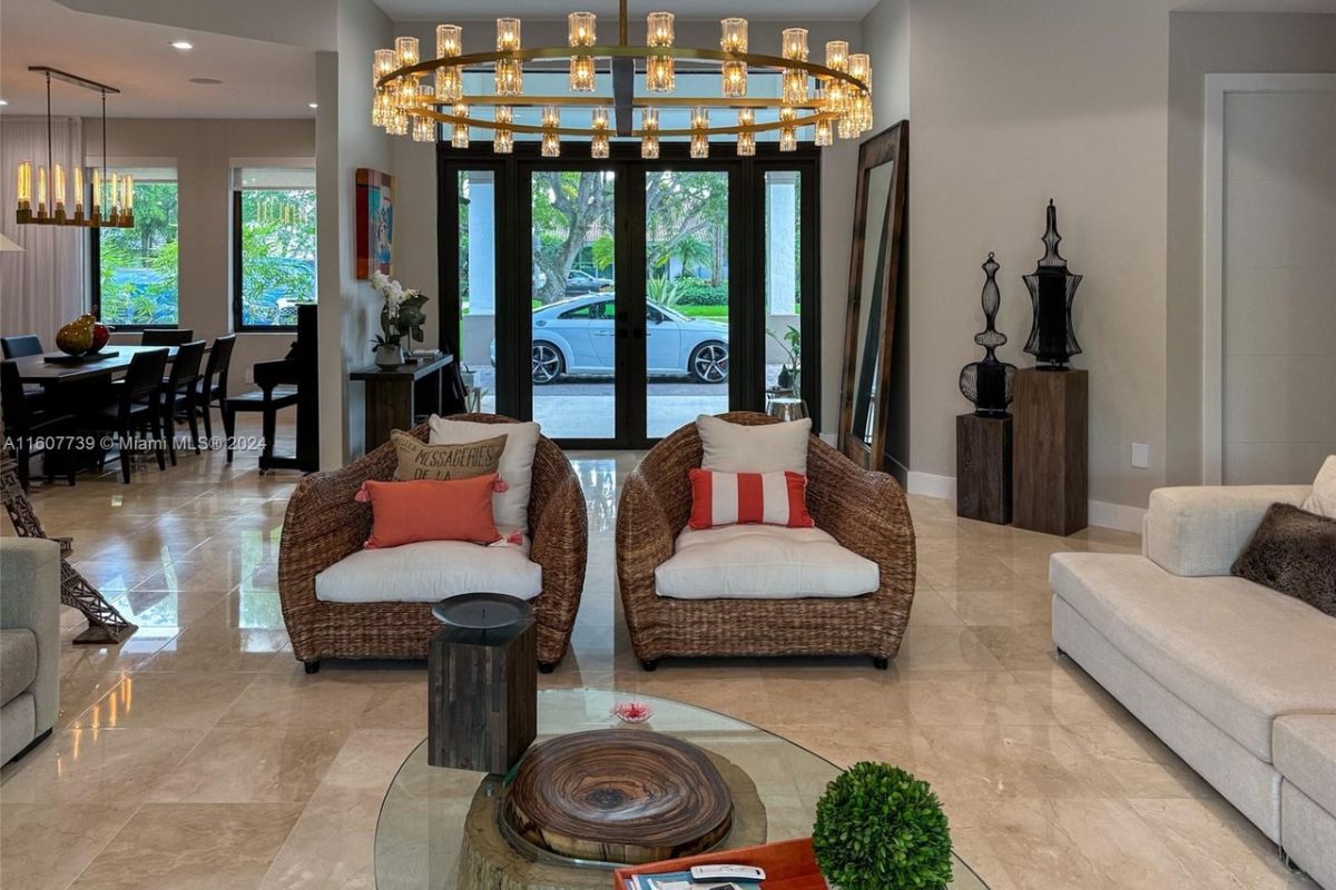 A living room with a chandelier, white couches, chairs, and a center table.