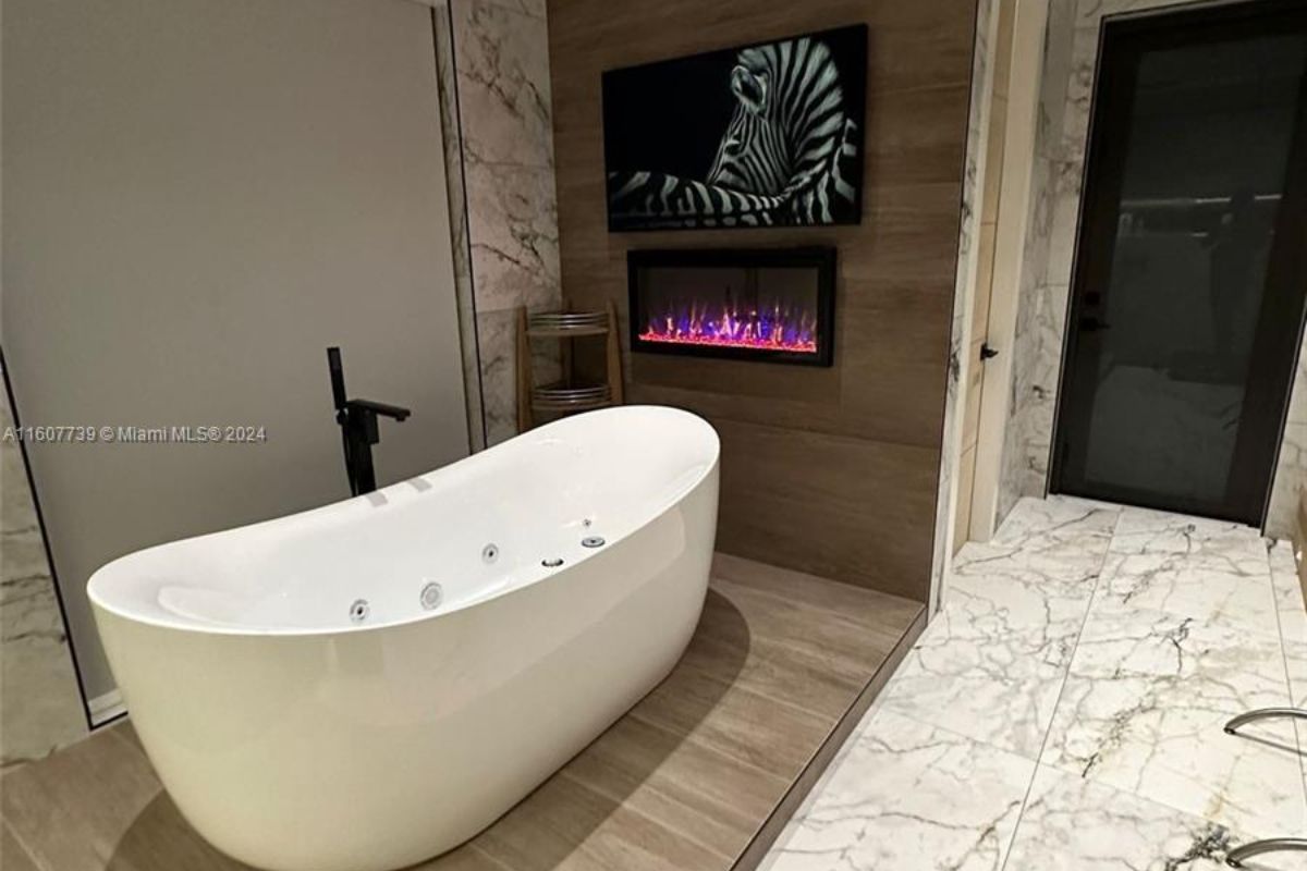 A bathroom with a TV, fireplace, and bathtub.