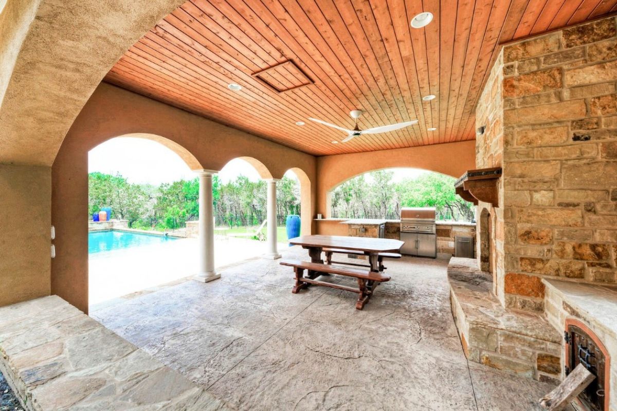 A patio with a table, benches, and a griller.