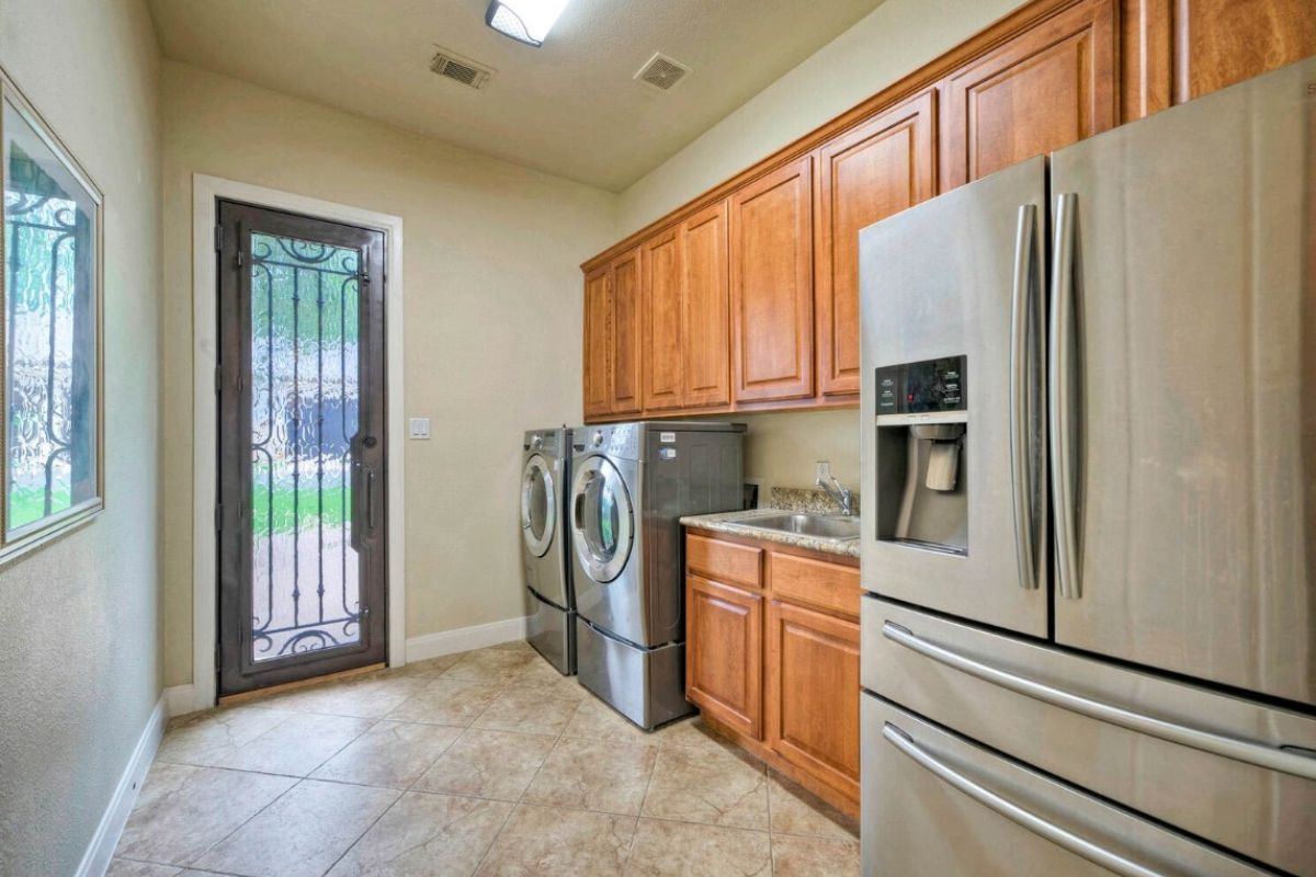 A laundry room with washing machines, a refrigerator, a sink, and cabinets.