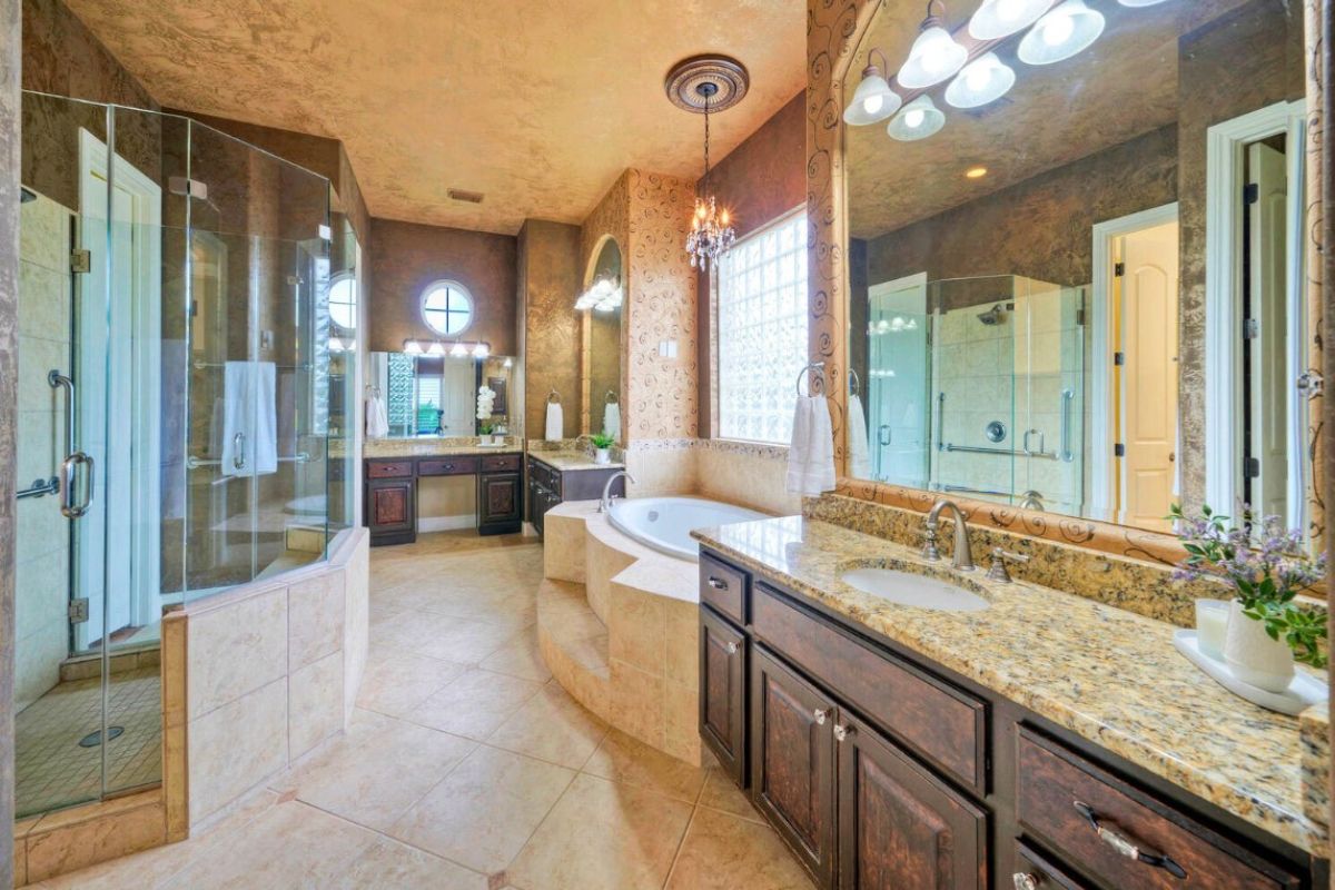 A bathroom with a vanity, mirror, cabinets, powder area, bathtub, and shower room.