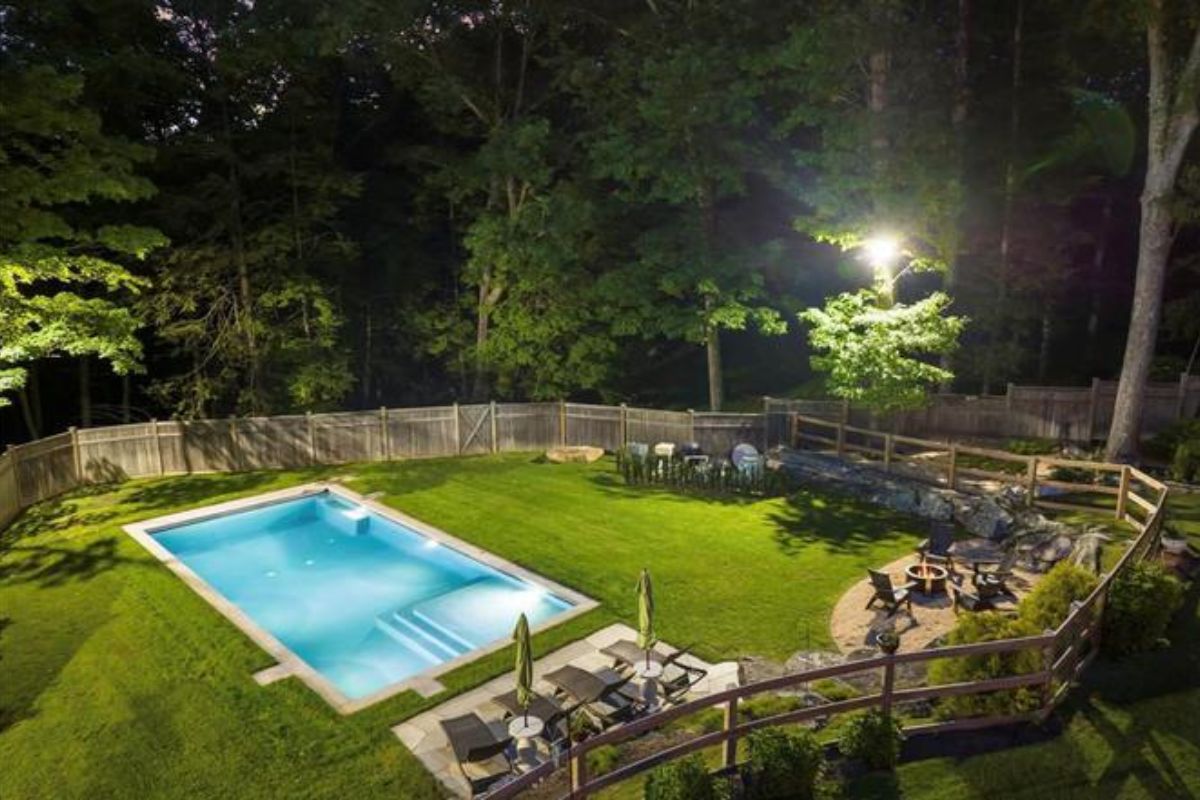 A swimming pool with a wooden fence surrounded by trees.