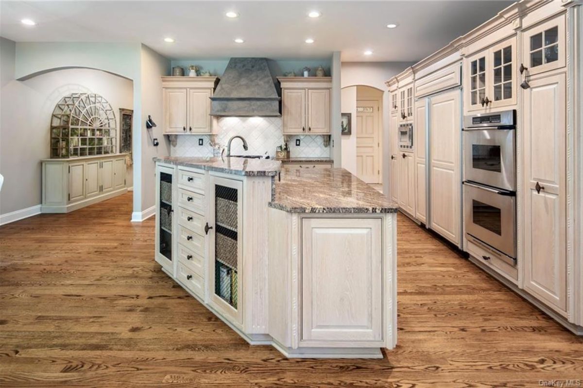 A kitchen with a center island, sink, cabinets, and kitchen appliances.