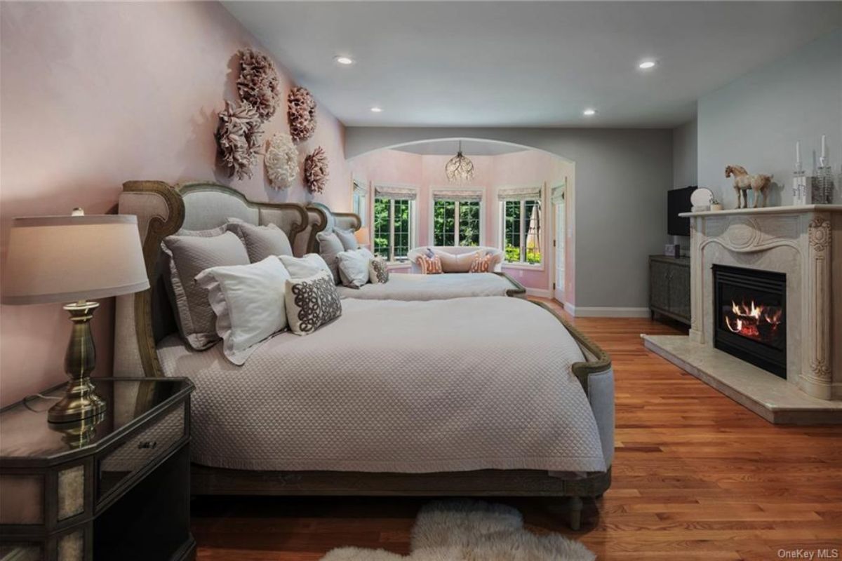 A bedroom with a bed, fireplace, windows, and a nightstand.