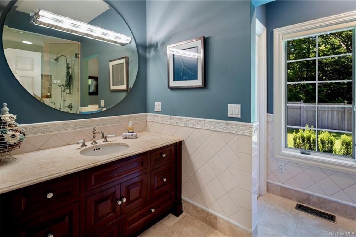 A bathroom with a vanity, mirror, and cabinets.