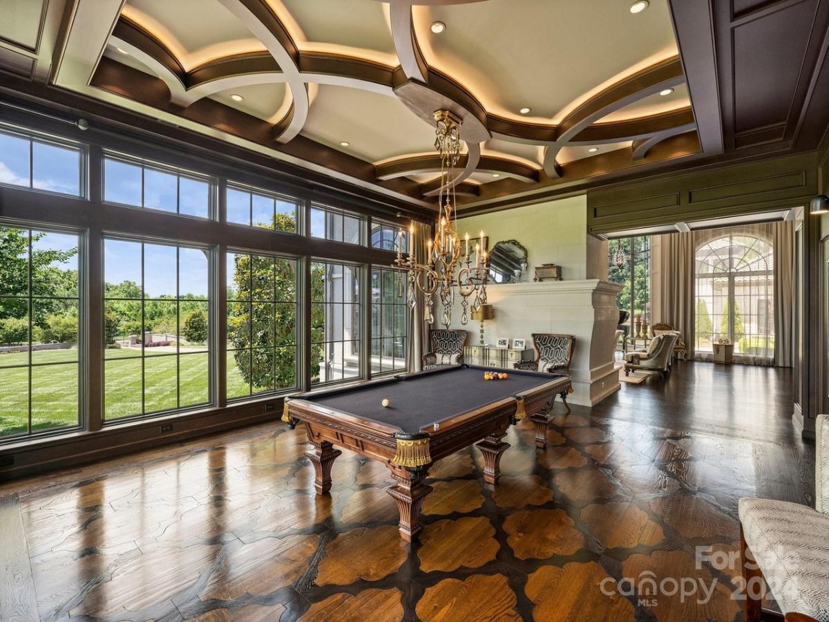 Billiards room with hardwood flooring, glass windows and coffered ceiling.