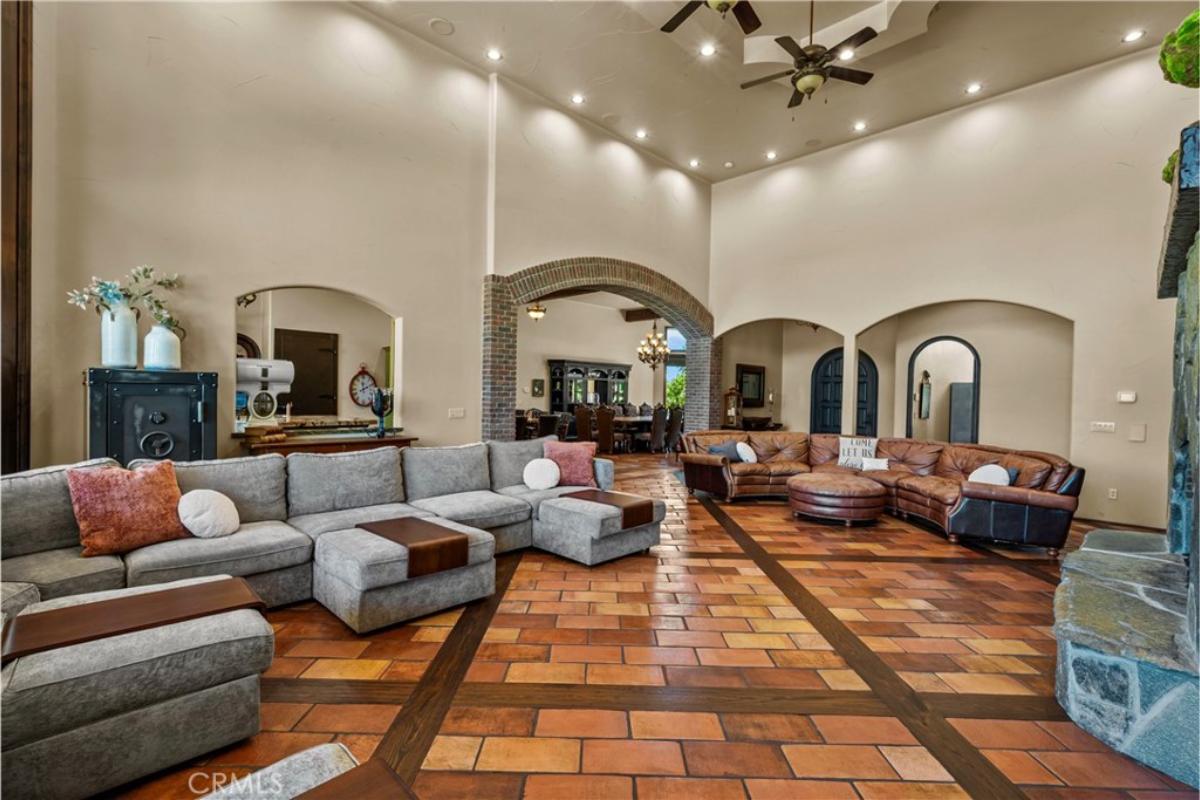 Living room with couches, tile flooring and custom lighting.