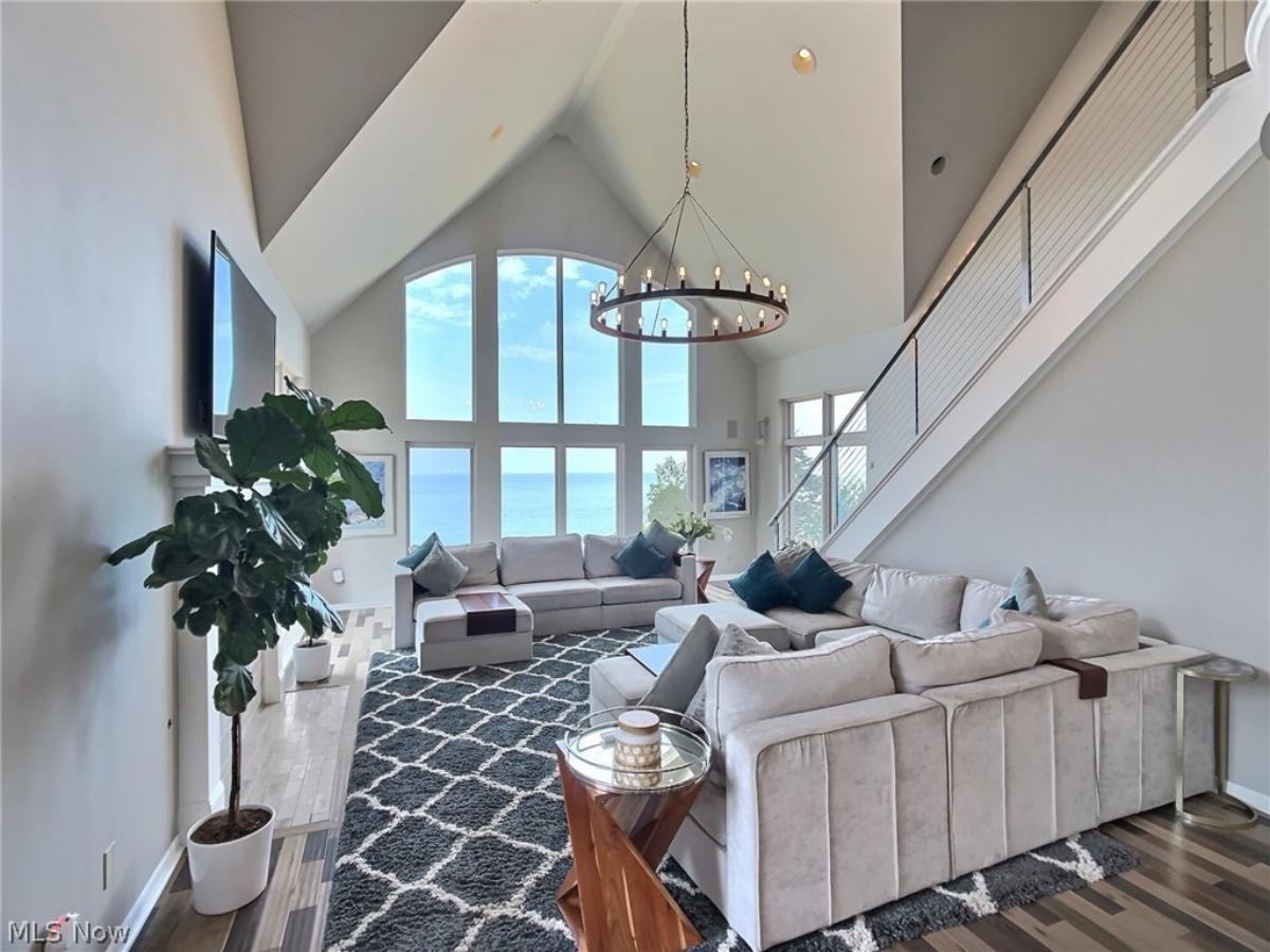 Living room with couches, TV and glass windows.