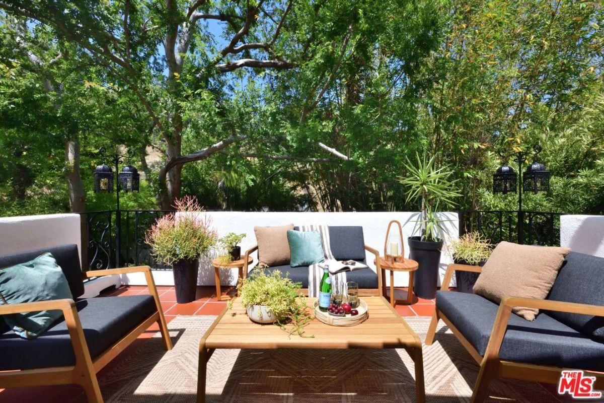 A patio with plants, chairs, and a center table.