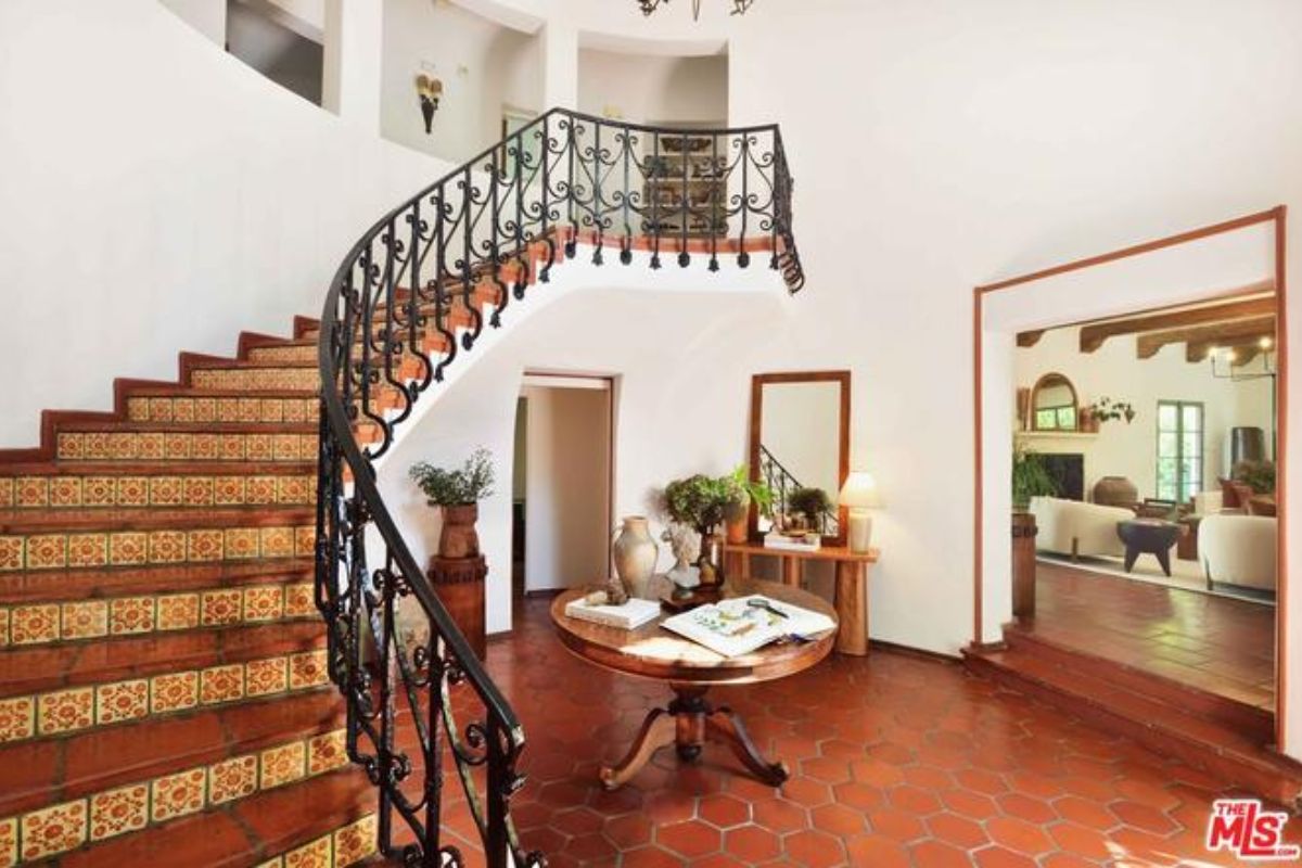 A foyer with a mirror, staircase, and a round center table.