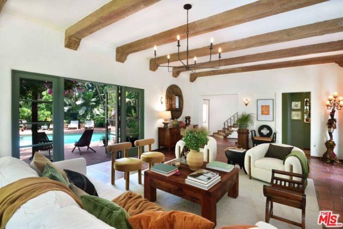 A living room with an exposed beam ceiling, couches, chairs, and a center table.