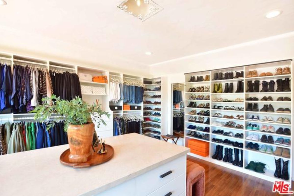 A walk-in closet with a center island, drawers, and shelves.