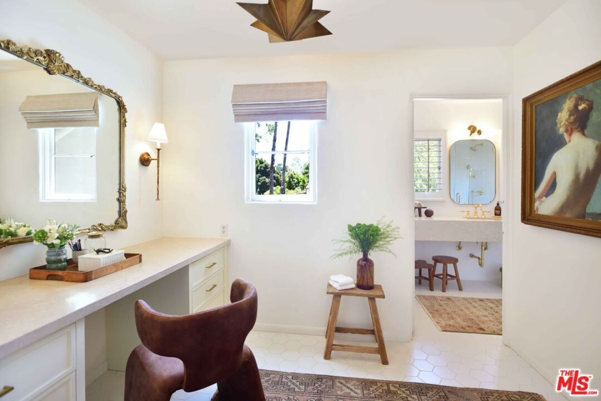 A powder room with a mirror, a table with drawers, and a chair.