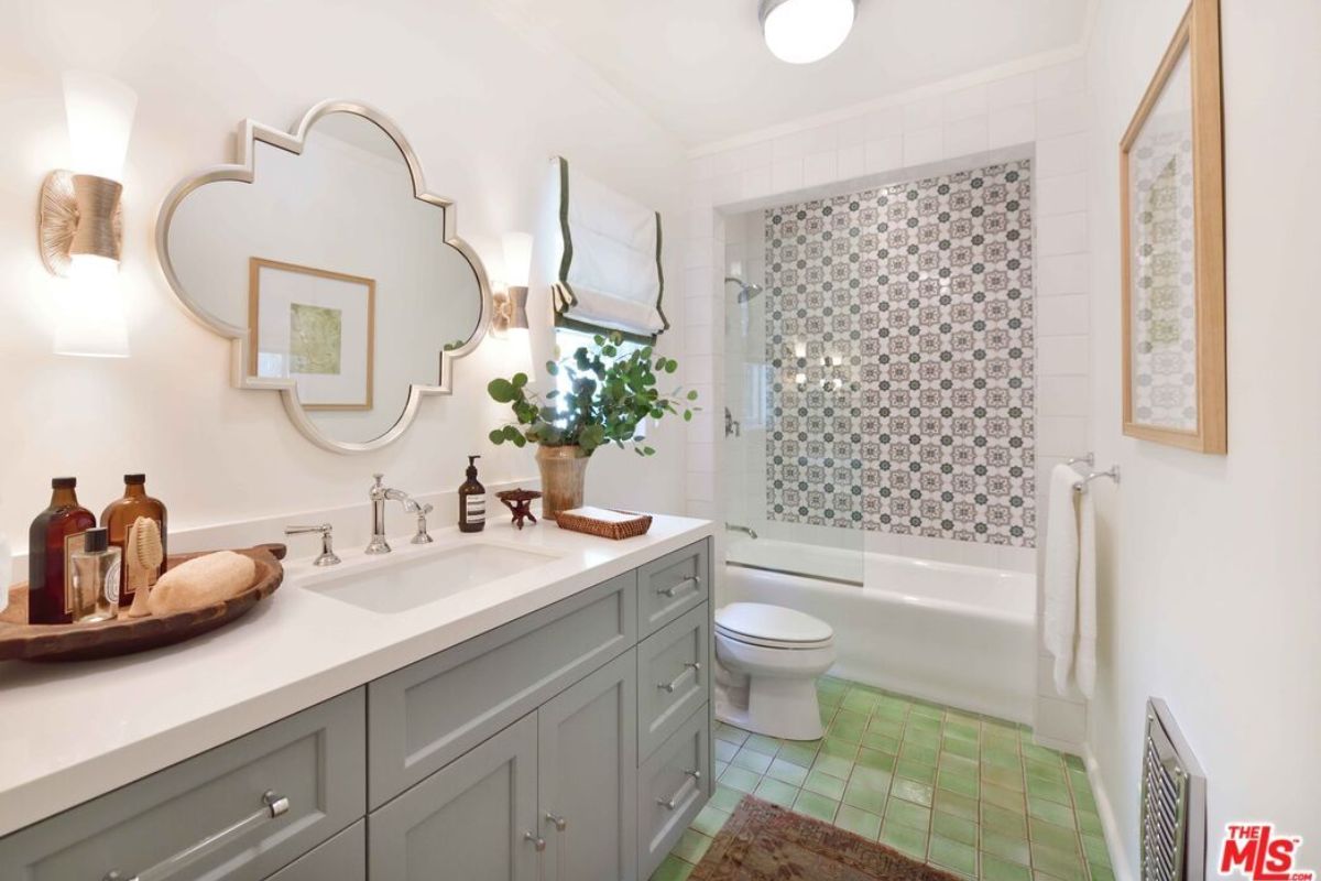 A bathroom with a vanity, mirror, cabinets, and a toilet.