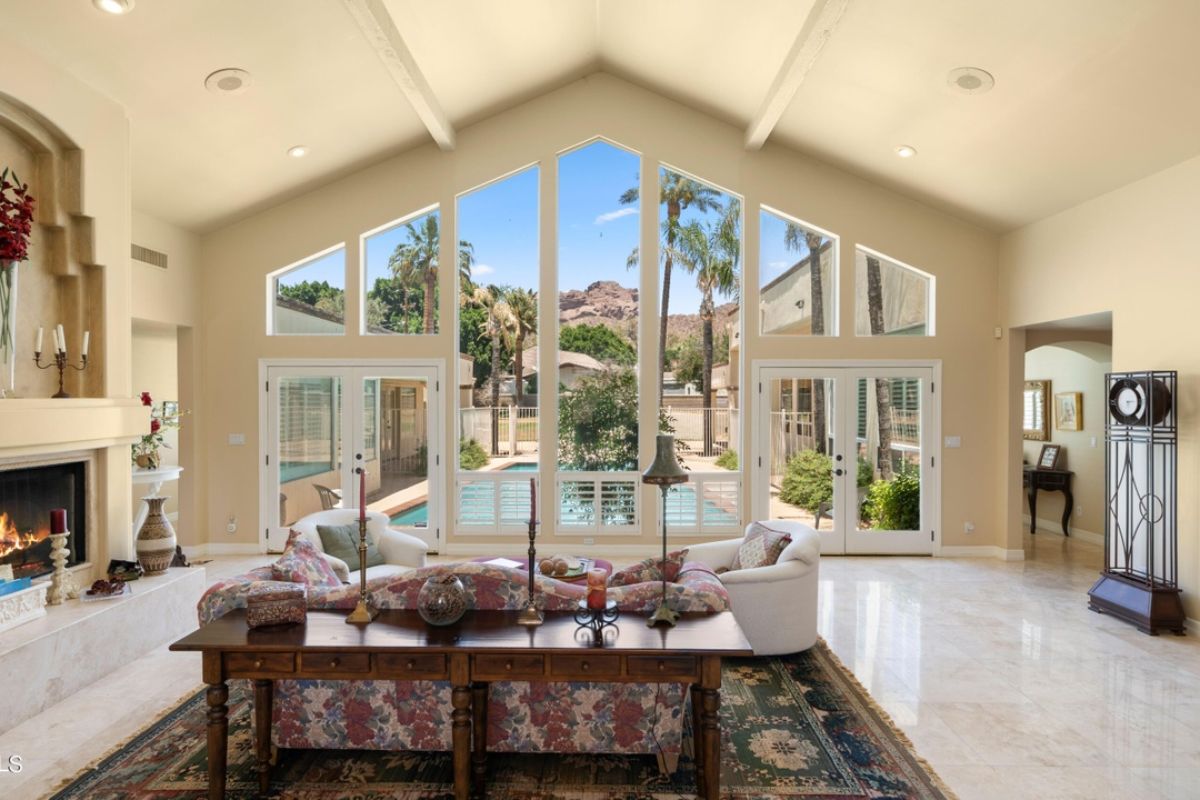 A living room with windows, a vaulted ceiling, fireplace, rug, and couches