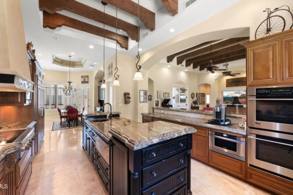 A kitchen with an exposed beam ceiling, center island, cabinets, and kitchen appliances.