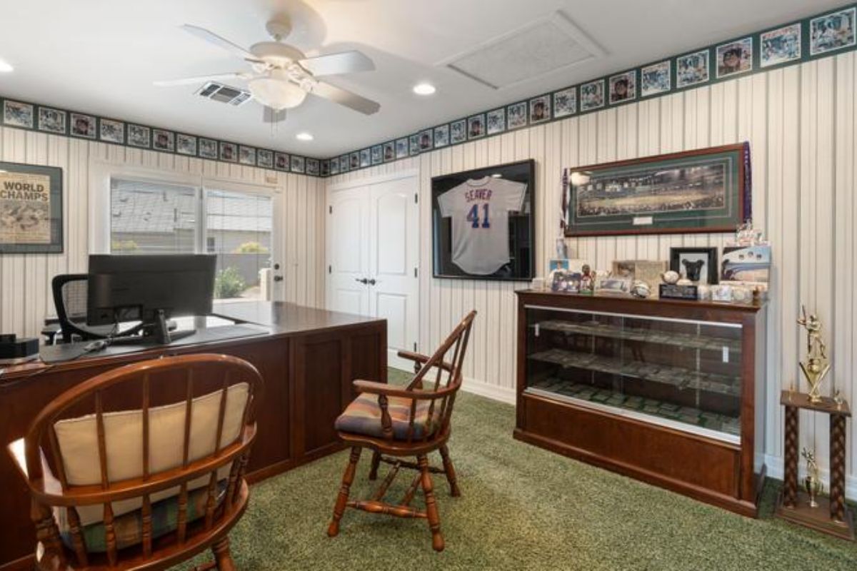 A home office with a ceiling fan, cabinet, desk, and chairs.