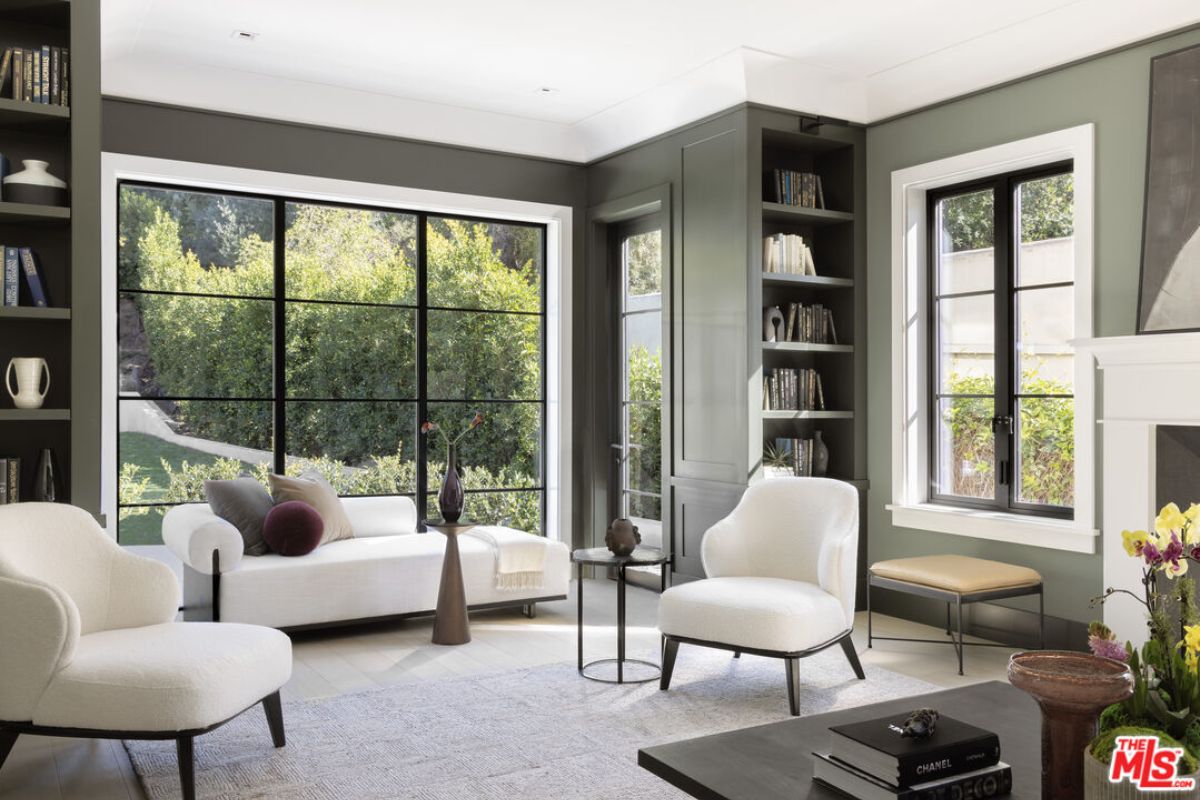 A living room with windows, shelves, couch, and chairs.