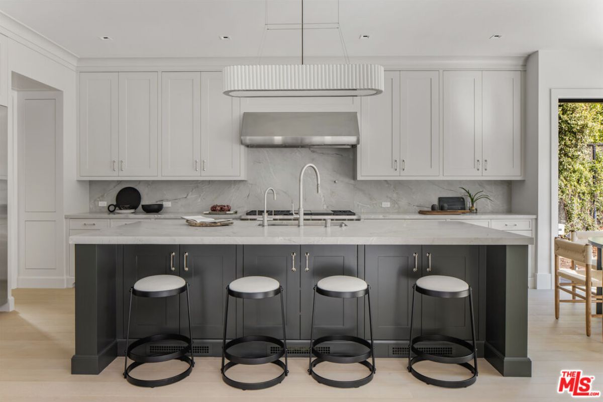 A kitchen with countertops, stools, sink, and cabinets.