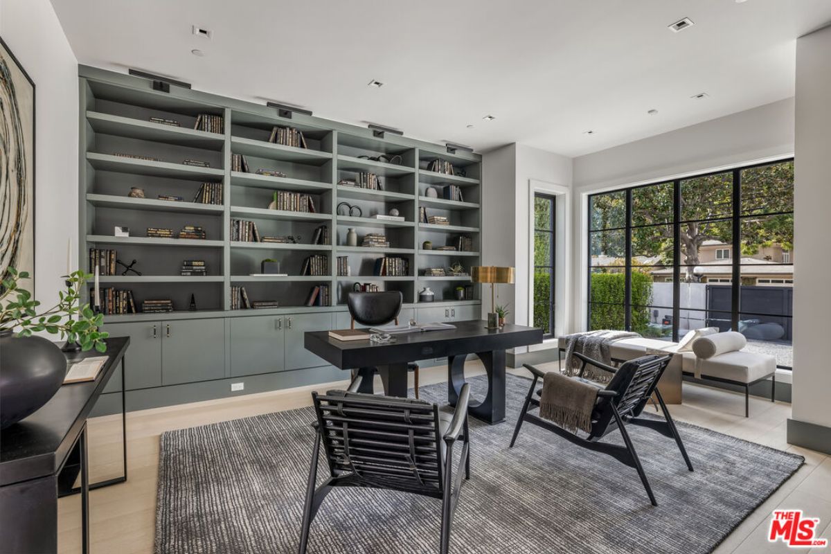 A home office with shelves, windows, cabinets, chairs, and a desk.