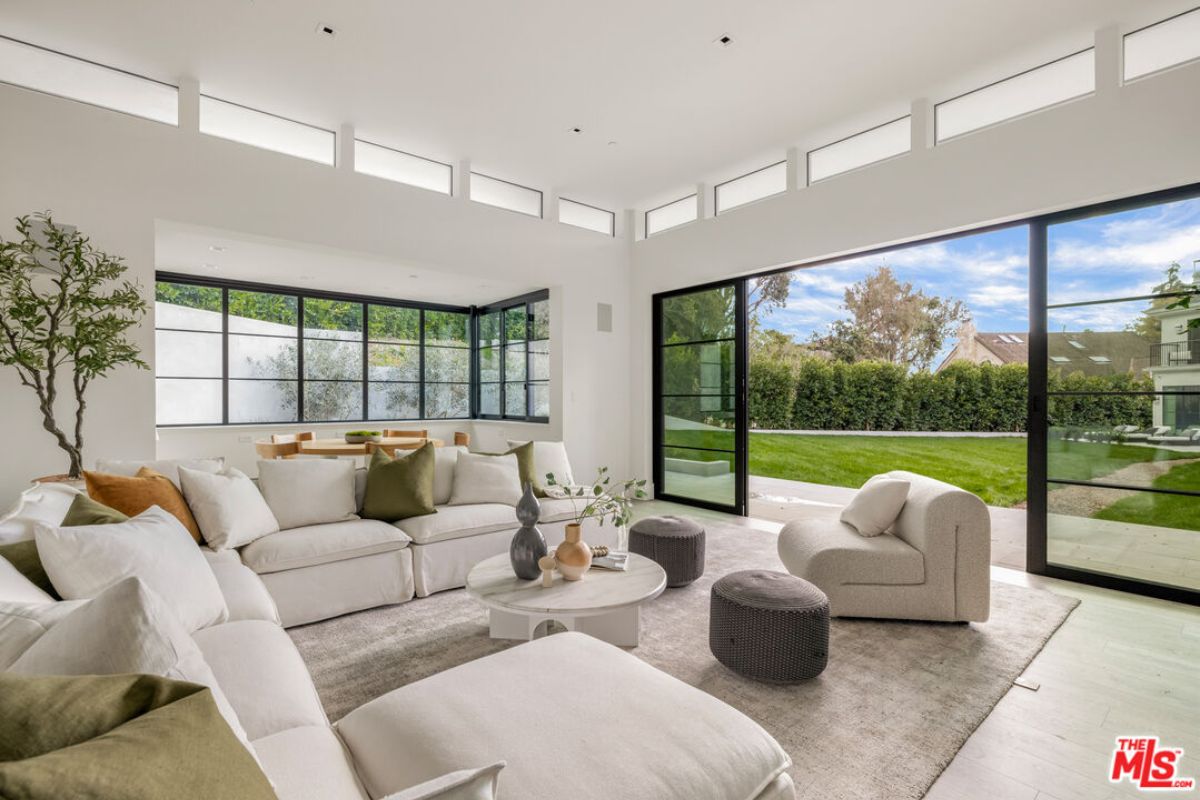 A living room with windows, white couches, a houseplant, and a center table.